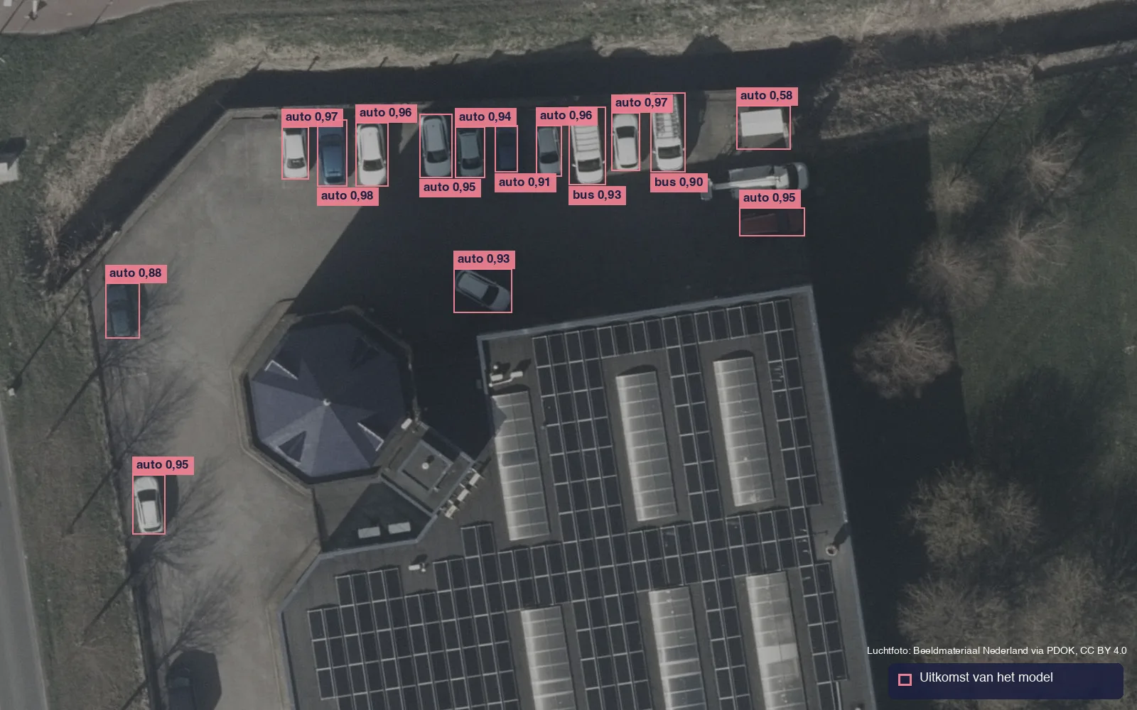 Luchtfoto van een parkeerplaats in Heerhugowaard met roze kaders van een AI-model rond auto's en busjes, ook rond een object dat geen auto is